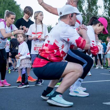 Grupa biegaczy przygotowuje się do biegu na 5 km w Parku Śląskim, w trakcie ciepłowania przed startem. (wygenerowano przez AI)
