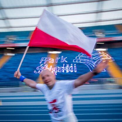 Bieg dla Flagi 2025 w Parku Śląskim - uczestnik z flagą, triumf w malowniczym otoczeniu. (wygenerowano przez AI)