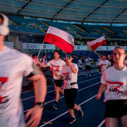 Bieg dla Flagi 2025 w Parku Śląskim, uczestnicy w białych koszulkach z czerwonymi i czarnymi akcentami, bieg na torze, patriotyczna atmosfera. (wygenerowano przez AI)