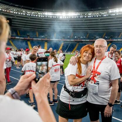 Na Biegu dla Flagi 2025 w Parku Śląskim uczestnicy w białych koszulkach z czerwonymi i czarnymi akcentami robią selfie. Atmosfera patriotyczna i festynowa. (wygenerowano przez AI)