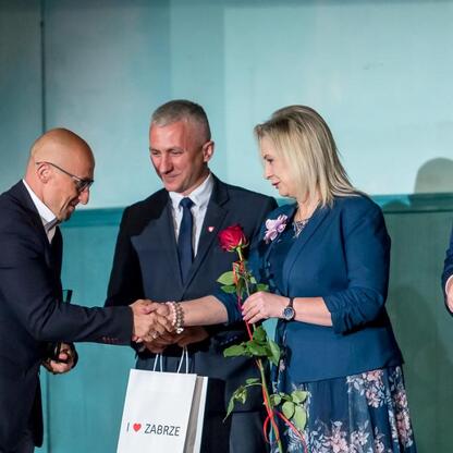 Rafał Adamczyk, członek Zarządu Województwa Śląskiego, wręcza kwiat kobiecie w trakcie uroczystości 
