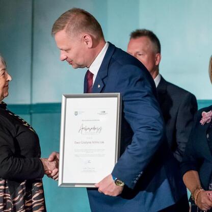 Członek Zarządu Województwa Śląskiego Rafał Adamczyk wręcza nagrodę ambasadorem srebrnego pokolenia w Teatrze Nowym w Zabrzu. (wygenerowano przez AI)