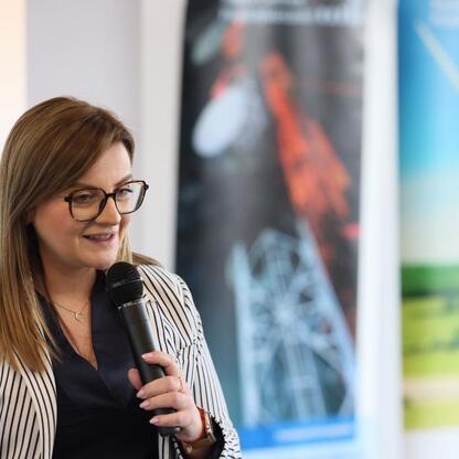 Kobieta przemawia na konferencji biznesowej w Arenie Zabrze, prezentując program wsparcia dla małych i średnich przedsiębiorstw. (wygenerowano przez AI)