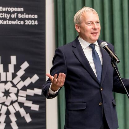 Marszałek Wojciech Saługa przemawia na podium podczas Europejskiego Miasta Nauki Katowice 2024. (wygenerowano przez AI)