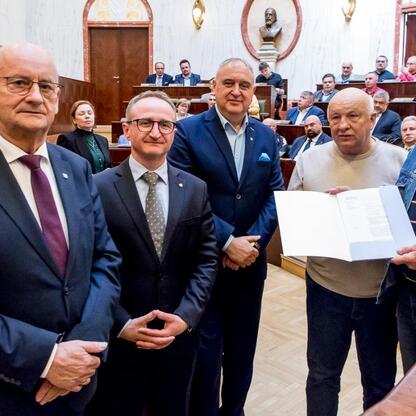 Wicemarszałek Grzegorz Boski wręcza certyfikaty 40 rodzinom ogrodowcom działkowym w Sali Sejmu Śląskiego. (wygenerowano przez AI)