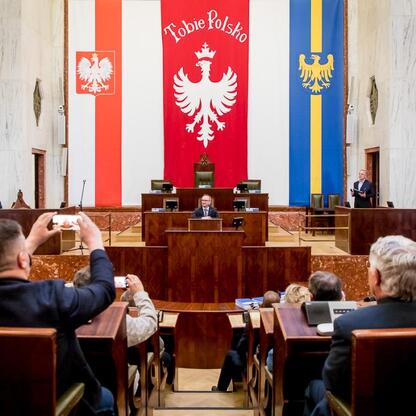 Wicemarszałek Grzegorz Boski przewodniczy ceremonii rozdania funduszy dla Rodzinnych Ogrodów Działkowych w Sali Sejmu Śląskiego. (wygenerowano przez AI)