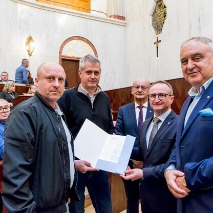 Wicemarszałek Grzegorz Boski wręcza certyfikaty zwycięzcom konkursu Rodzinnych Ogrodów Działkowych w Sali Sejmhu Śląskiego. (wygenerowano przez AI)