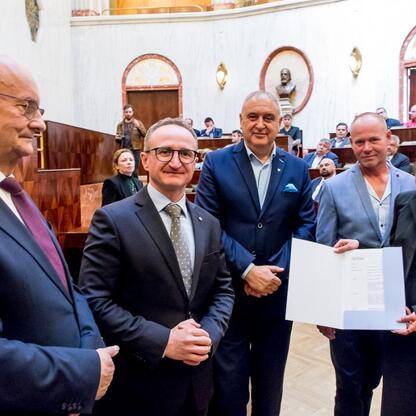 Wicemarszałek Grzegorz Boski wręcza certyfikaty fundacji 40 rodzinnym ogrodom działkowym w Sali Sejmu Śląskiego. (wygenerowano przez AI)