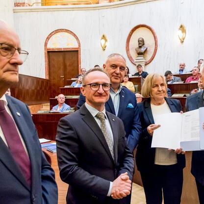 Wicemarszałek Grzegorz Boski i radni Marek Bieniek i Bronisław Karasek wręczają certyfikaty funduszy na rodzinną ogrodnictwo w Sali Sejmu Śląskiego. (wygenerowano przez AI)
