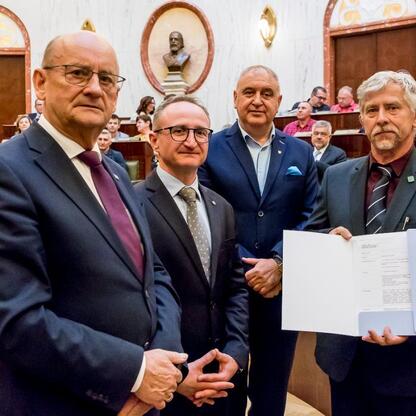 Wicemarszałek Grzegorz Boski i radni Sejmiku Województwa Śląskiego uczestniczą w uroczystości wręczenia dofinansowania dla Rodzinnych Ogrodów Działkowych. (wygenerowano przez AI)