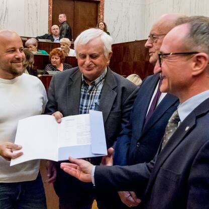 Grzegorz Boski, wicemarszałek Województwa Śląskiego, wręcza certyfikaty funduszy 40 rodzinom działkowym w Sali Sejmu Śląskiego. (wygenerowano przez AI)