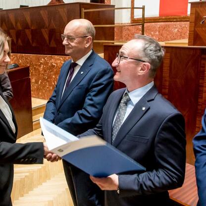 Wicemarszałek Grzegorz Boski wręcza dokumenty przedstawicielom gmin podczas ceremonii w Sali Sejmu Śląskiego. (wygenerowano przez AI)