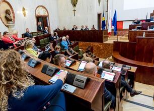 Dwa parlamentarzyści w rozmowie w sali posiedzeń Sejmiku Śląskiego, omawiają Krajowy Plan Odbudowy i budżet 2025. (wygenerowano przez AI)