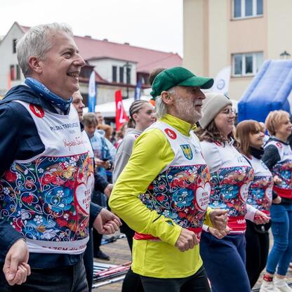 Zwycięzcy 26. Biegu po Nowe Życie, wspierające polską transplantologię, uściskują ręce i uśmiechają się, podkreślając ducha solidarności. (wygenerowano przez AI)