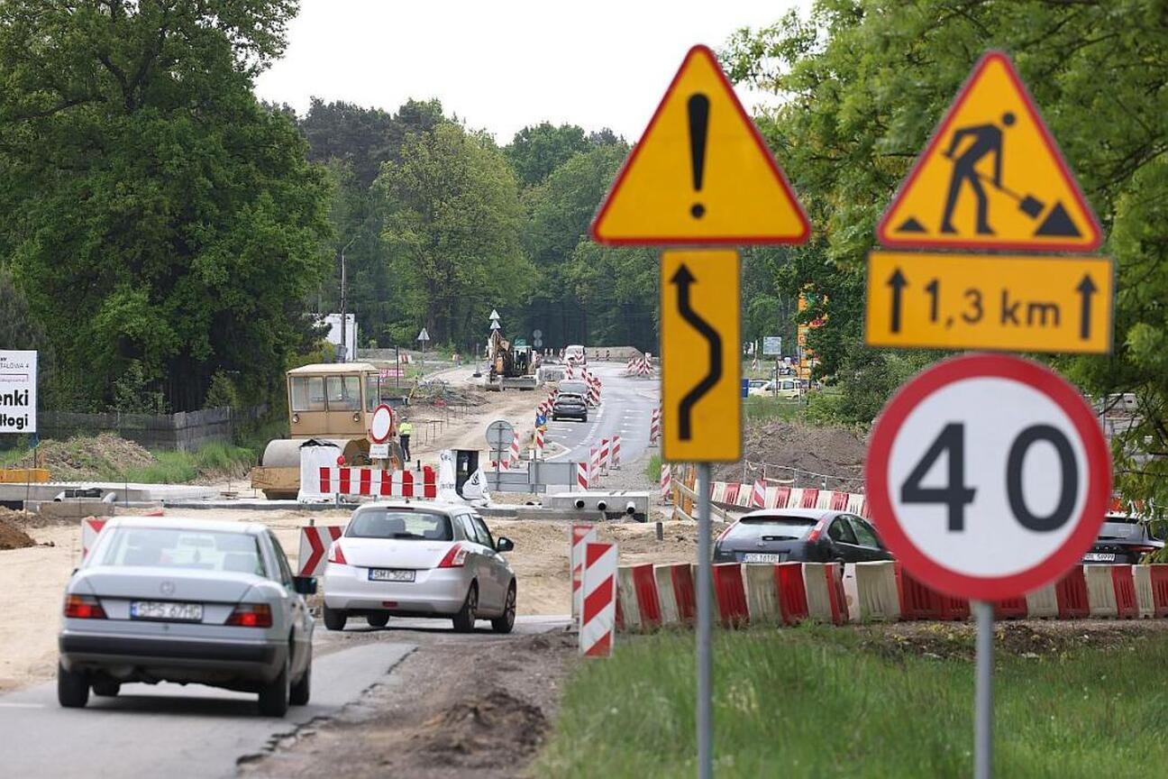 Na budowie drogi wojewódzkiej DW 928, modernizacji prowadzonej przez Budimex S.A., widoczny jest Ciągnik Caterpillar, a pracownicy kontrolują jego stan. (wygenerowano przez AI)