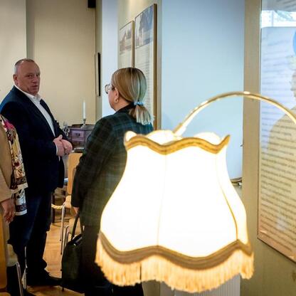 Grupa osób w Muzeum, rozmawiają o eksponatach, wokół lampy. (wygenerowano przez AI)
