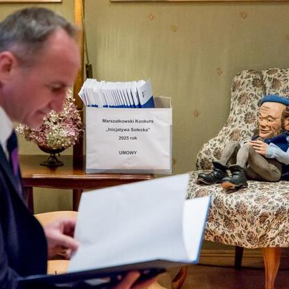 Wicemarszałek Grzegorz Boski prezentuje umowy sołeckim inicjatywom w Górkach Wielkich. (wygenerowano przez AI)