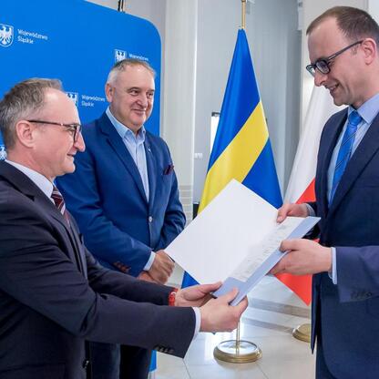 Wicemarszałek Grzegorz Boski wręcza dokumenty przedstawicielom samorządów w Silesia Voivodeship Marshal's Office. (wygenerowano przez AI)