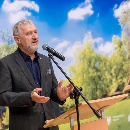 Mężczyzna w ciemnym garniturze przemawia z podium podczas jubileuszu 50-lecia Muzeum 