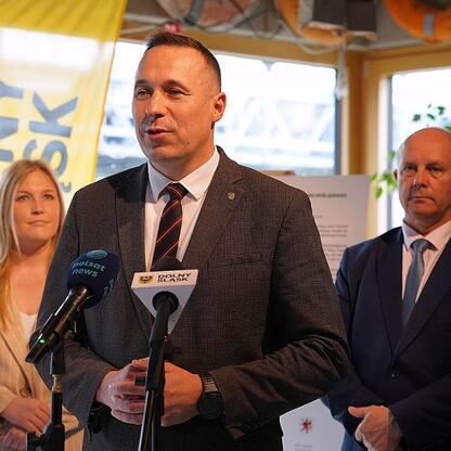 Joanna Bojczuk, Członek Zarządu Województwa Śląskiego, przemawia na podium podczas konferencji prasowej w Odra Centrum. (wygenerowano przez AI)
