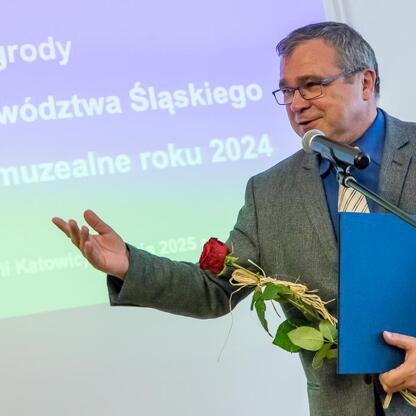 Na Święcie Muzealnictwa wręczono nagrody za Wydarzenie Muzealne roku 2024. Osoba na zdjęciu odbiera nagrodę, trzymając bukiet i certyfikat. (wygenerowano przez AI)