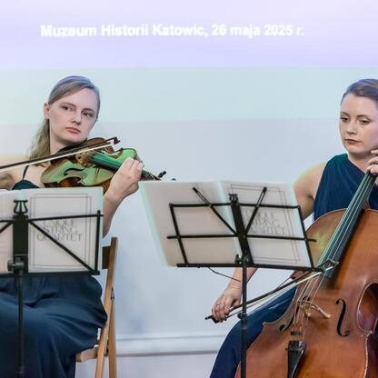 Dwóch muzyków grających na skrzypcach i wiolonczeli podczas Święta Muzealnictwa w Muzeum Historii Katowic. (wygenerowano przez AI)