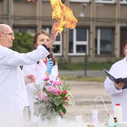 Grupa naukowców w białych kamizelkach demonstruje eksperyment chemiczny na terenie Uniwersytetu Śląskiego. (wygenerowano przez AI)