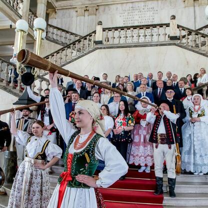 Widoczna jest scena z XV sesji Sejmiku Województwa Śląskiego, gdzie folklorystyczne tradycje świętowane są w grandioznym sali z marmurowymi schodami i ozdobnymi balustradami. (wygenerowano przez AI)