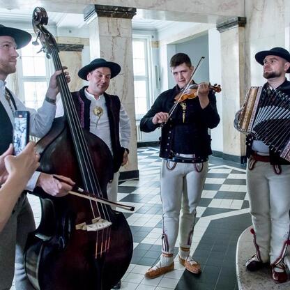 Muzycy w tradycyjnych strojach polskich folkowych występują w marblednym sali, uczestniczą w Tydzień Kultury Beskidzkiej w Śląskim. (wygenerowano przez AI)