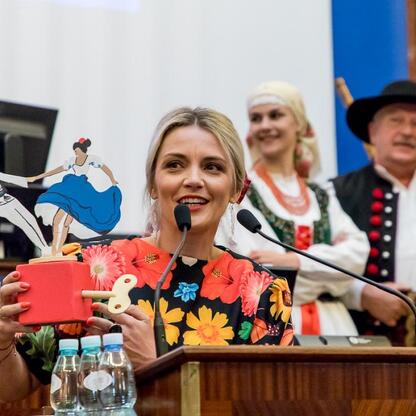 W czasie XV sesji Sejmiku Województwa Śląskiego, kobieta prezentuje kolorowy wycinany folklorystyczny taniec, symbolizujący bogactwo kulturowe regionu. (wygenerowano przez AI)