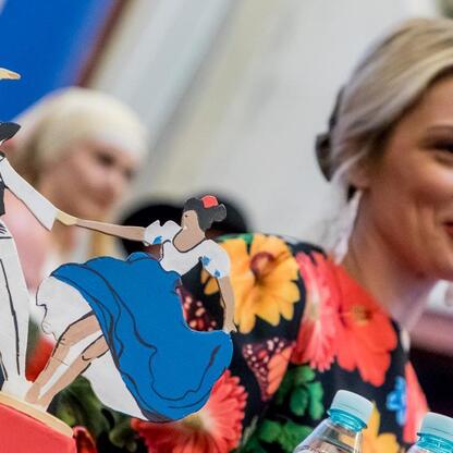 W czasie XV sesji Sejmiku Województwa Śląskiego dyskutowana jest o folklorze, z mikrofonem mówiąca kobieta przedstawia kolorowe papierowe postacie w tradycyjnych strojach. (wygenerowano przez AI)