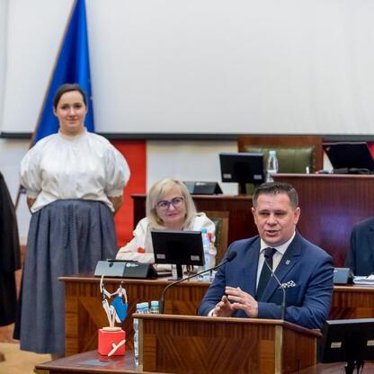 Widoczna jest sesja Sejmiku Województwa Śląskiego, gdzie uczestnicy w tradycyjnych strojach uczestniczą w dyskusji. (wygenerowano przez AI)