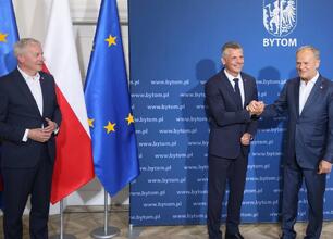 Grupa ludzi w garniturach bierze selfie, podczas spotkania z premierem Donaldem Tuskiem i innymi oficjali. (wygenerowano przez AI)