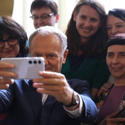 Grupa ludzi w garniturach bierze selfie, podczas spotkania z premierem Donaldem Tuskiem i innymi oficjali. (wygenerowano przez AI)