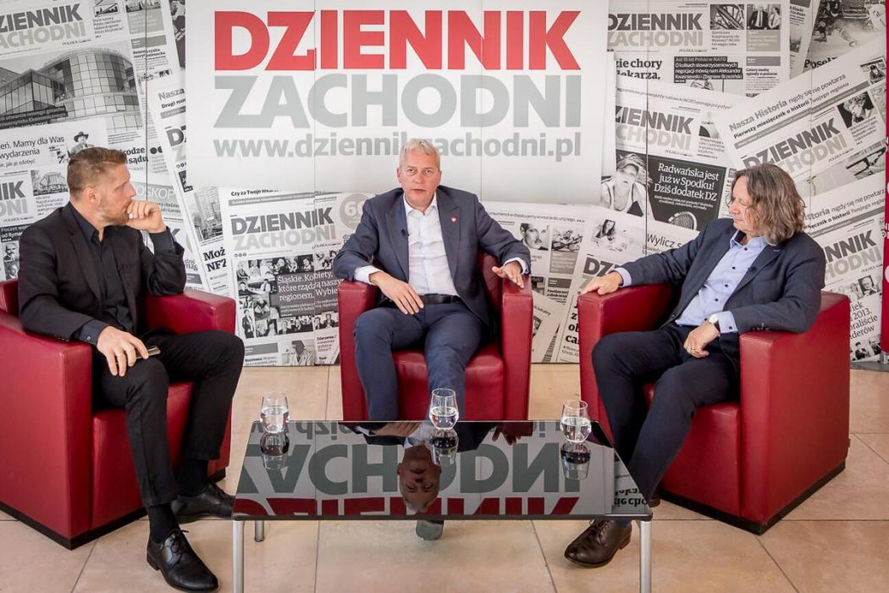 Na zdjęciu widoczny jest mężczyzna w garniturze, który dyskutuje o przyszłości edukacji i nauki w regionie Śląskim. (wygenerowano przez AI)