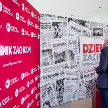 Na zdjęciu widoczny jest mężczyzna w garniturze, który dyskutuje o przyszłości edukacji i nauki w regionie Śląskim. (wygenerowano przez AI)