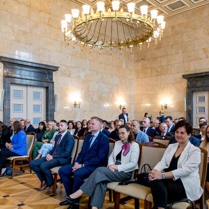 W ścisłym, formalnym zborze w gmachu administracyjnym Śląska, członek Zarządu Województwa Rafał Adamczyk przemawia o inwestycjach w edukację i rozwój młodzieży. (wygenerowano przez AI)