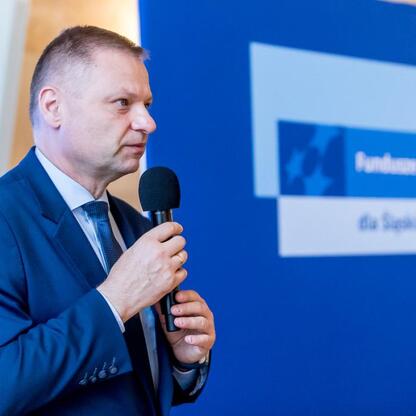Rafał Adamczyk, członek Zarządu Województwa Śląskiego, przemawia na konferencji o inwestycjach w edukację. (wygenerowano przez AI)