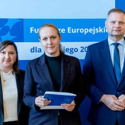 Członkowie Zarządu Województwa Śląskiego wręczają certyfikaty beneficjentom programu Fundusze Europejskie dla Śląska 2021-2027. (wygenerowano przez AI)