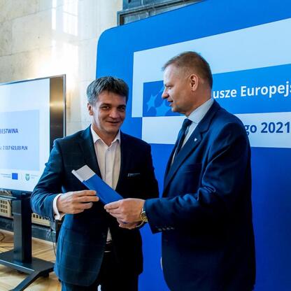 Członek Zarządu Województwa Śląskiego Rafał Adamczyk prezentuje dokument, podczas ceremonii wręczenia gratulacyjnych list do beneficjentów programu edukacyjnego. (wygenerowano przez AI)