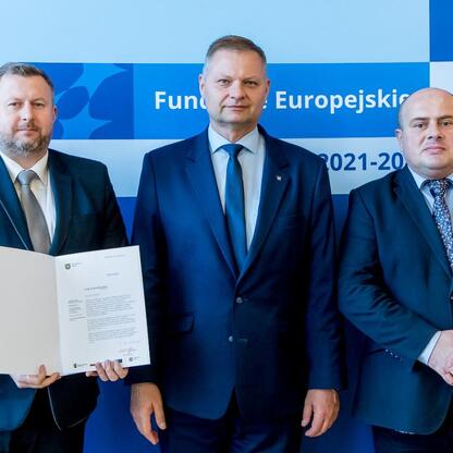 Członek Zarządu Województwa Śląskiego Rafał Adamczyk wręcza listy gratulacyjne beneficjentom projektów edukacyjnych finansowanych z Europejskich Funduszy 2021-2027. (wygenerowano przez AI)