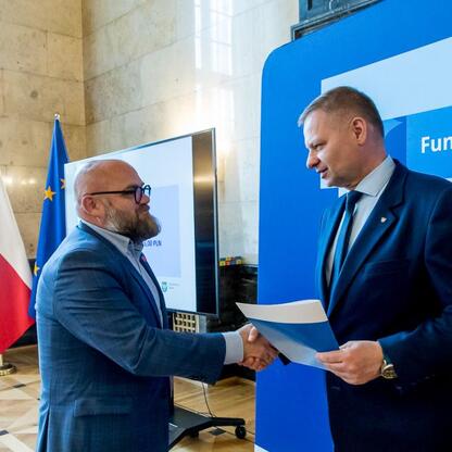 Członek Zarządu Województwa Śląskiego Rafał Adamczyk wręcza listy gratulacyjne beneficjentom projektów edukacyjnych finansowanych z Europejskich Funduszy dla Śląska 2021-2027. (wygenerowano przez AI)