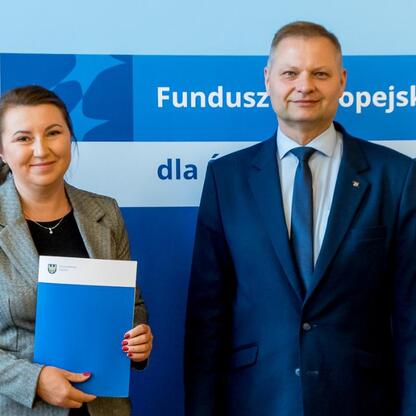 Członek Zarządu Województwa Śląskiego Rafał Adamczyk i jego współpracownica prezentują dokumenty z programu Fundusze Europejskie dla Śląska 2021-2027. (wygenerowano przez AI)