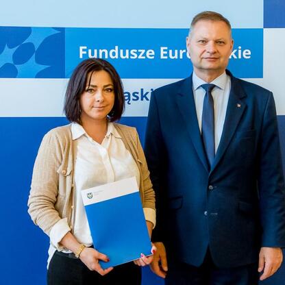 Rafał Adamczyk i Joanna Bojczuk przedstawiają listy gratulacyjne dla beneficjentów programu Funduszy Europejskich w Śląsku. (wygenerowano przez AI)