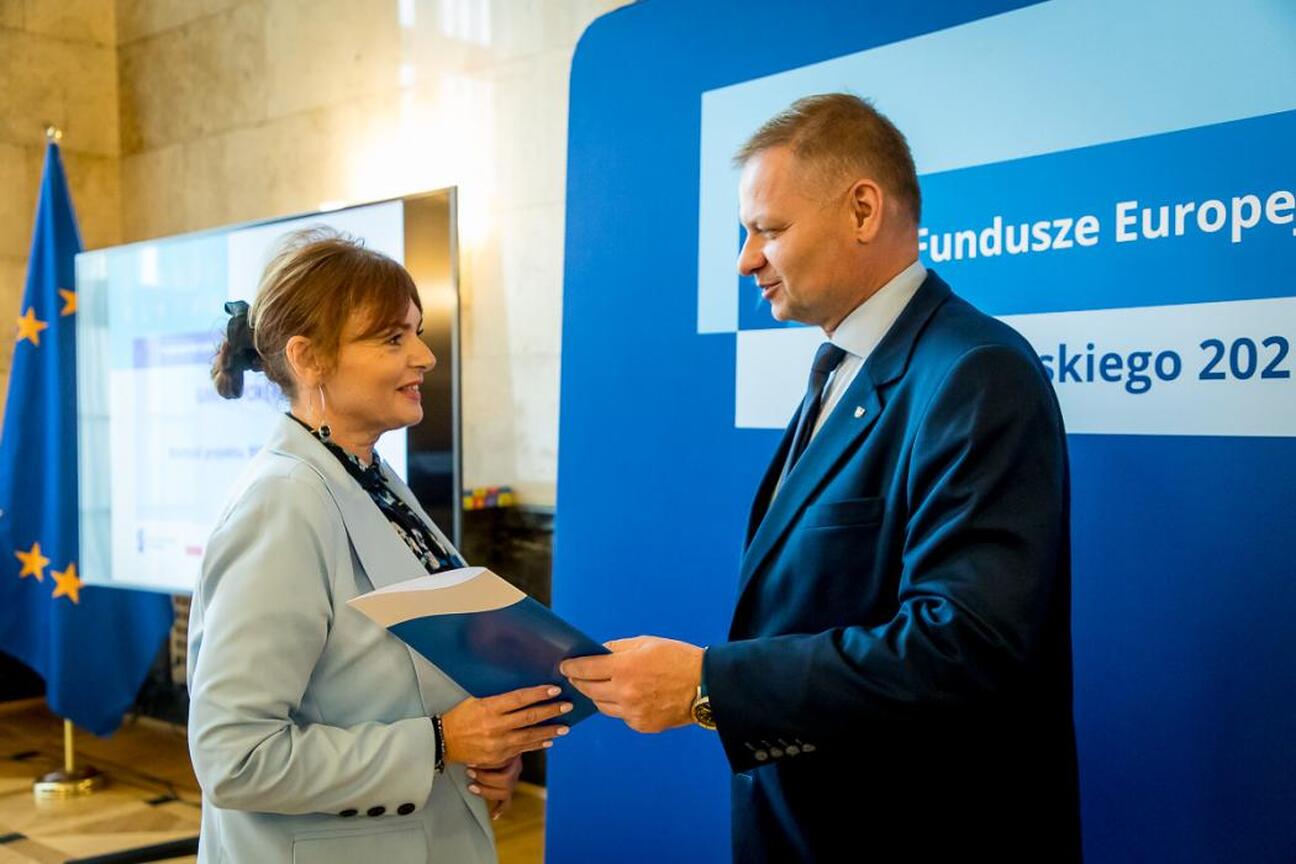 Joanna Bojczuk i Rafał Adamczyk wręczają listy gratulacyjne beneficjentom projektów edukacyjnych w ramach Funduszy Europejskich dla Śląska 2021-2027. (wygenerowano przez AI)