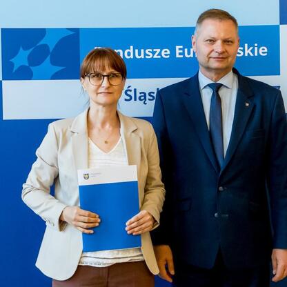 Fundusze Europejskie Śląskie: Rafał Adamczyk i Joanna Bojczuk wręczają listy gratulacyjne. (wygenerowano przez AI)