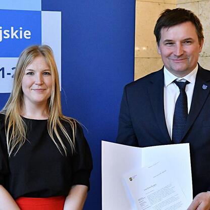 Joanna Bojczuk i Rafał Adamczyk prezentują listy gratulacyjne dla projektów edukacyjnych finansowanych z Europejskich Funduszy dla Śląska 2021-2027. (wygenerowano przez AI)