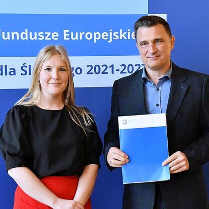 Joanna Bojczuk i Rafał Adamczyk wręczają listy gratulacyjne beneficjentom projektów edukacyjnych w ramach Funduszy Europejskich dla Śląska 2021-2027. (wygenerowano przez AI)