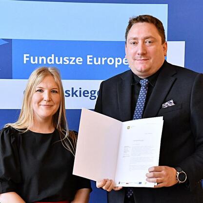 Joanna Bojczuk i Rafał Adamczyk prezentują listy gratulacyjne dla beneficjentów programu Fundusze Europejskie dla Śląska 2021-2027. (wygenerowano przez AI)
