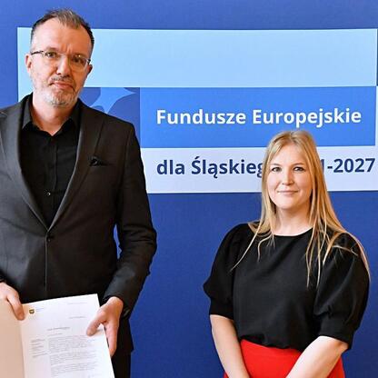 Joanna Bojczuk i Rafał Adamczyk wręczają listy gratulacyjne beneficjentom projektów edukacyjnych w ramach Funduszy Europejskich dla Śląska 2021-2027. (wygenerowano przez AI)